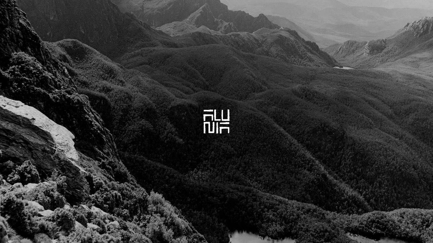 Alunia monogram, which reads the same upside down, over a mountain ridge photograph